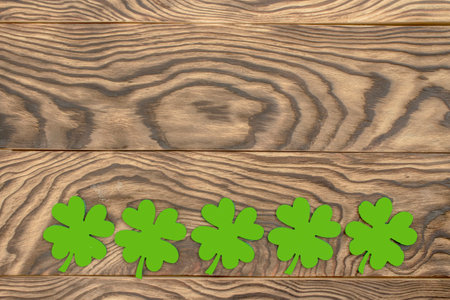Frame of four-leaf clover and light lights. Wooden background with clover leaves. St. Patrick's Day. Textured wood, blank for holiday greetings. flat layout. copyspace.の写真素材