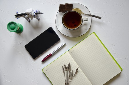 Workspace with notepad, cup of tea on a white background. Flat lay, top view office desk writing desk. Workplace freelancer. Copyspace.の写真素材
