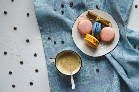 A cup of hot cappuccino with cinnamon and multi-colored cake macaroonsの写真素材