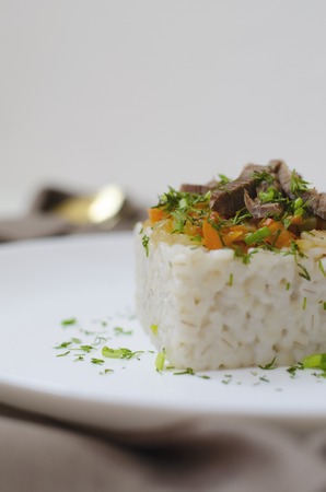On a white background barley porridge is served on a white plate, in the background tableware is served with a textile napkin and tied with a rope. Vertical orientation.の写真素材