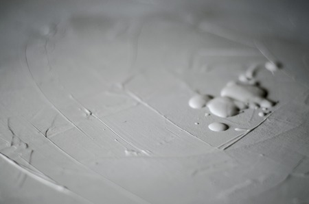 Closeup of wall painting using a roller. On the right side large drops of paint. Coloring in white-gray color, concrete. Home repair, interior design. Rough finish.の写真素材