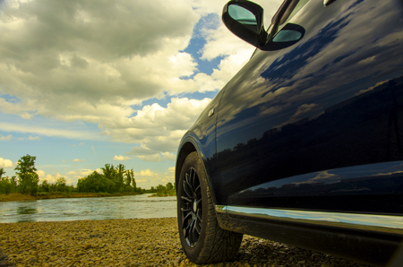 Travel in the summer. Horizontal layout, the wheel close-up in the open air against the background of the sky. Car on a country road on the background of the riverの写真素材