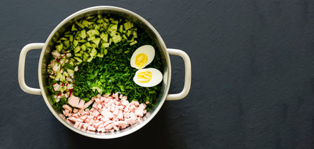 Traditional Russian summer cold soup okroshka with kefir in a saucepan on a dark background. The...