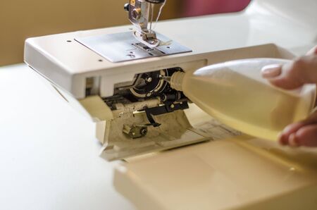 Sewing machine. Work in the light built into the hardware lamp. Steel needle with looper and leg close up. Preparation for work, the seamstress serves the sewing machine after work.の写真素材