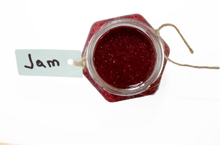 Glass jar with strawberry jam. View from above Tag with the inscription. Horizontal. Isolated