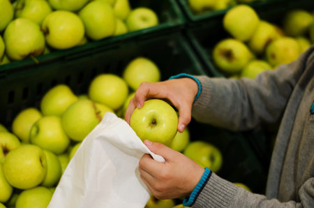 Children's hands put apples in a bag of cotton at the supermarket. Reusable environmental shopping bag. Zero waste concept - reuse.の写真素材