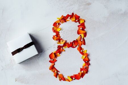 The number eight is laid out of rose cakes and decorated with many white flowers. On the left side, the gift box is decorated with a ribbon with a bow. Gift Concept for International Womens Day. Copy spaceの写真素材