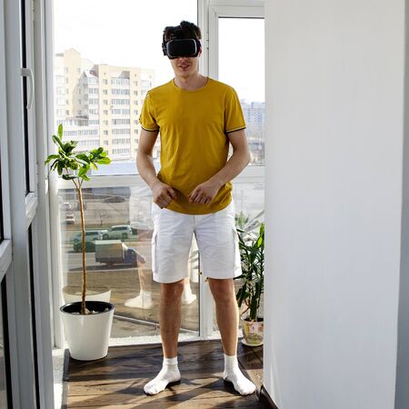 Young man using a VR headset to play fighting game. Portrait of a young man with virtual reality glasses. Virtual games in a confined space. Faceless.の写真素材