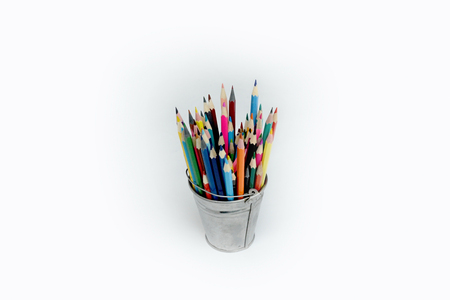 a lot of colored children's pencils for drowing in a tin bucket on a white backgroundの写真素材