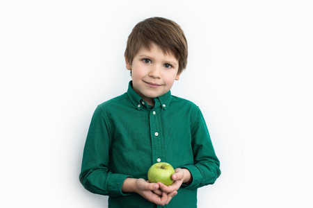 Boy in a green shirt holds a green apple in his hands, emotions. Healthy food