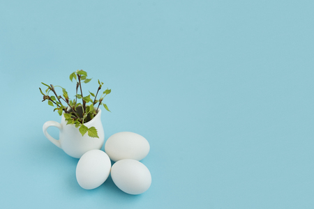 happy easter egg and branch with young leaves on turquoise backgroundの写真素材