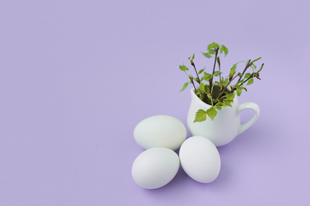 happy easter egg and branch with young leaves on lilac backgroundの写真素材