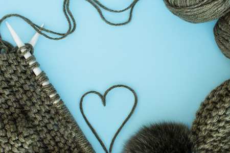 knitting, needlework, yarn, scarf and hat with a pompon green on a blue background, space for text, free spaceの写真素材