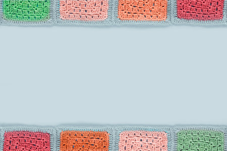 Grandma  crocheted  lace tablecloth of multicolored squares ornament on a gray background, top view,...