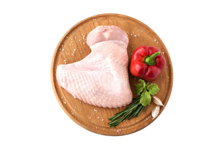 raw turkey wing, part of chicken poultry carcass, on a wooden round board with pepper and rosemary on a white background, isolate.の写真素材