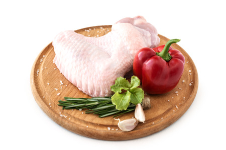 raw turkey wing, part of chicken poultry carcass, on a wooden round board with pepper and rosemary on a white background, isolate.の写真素材