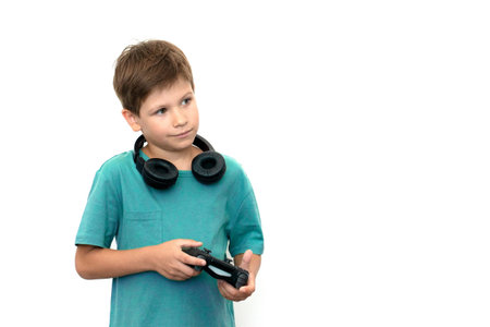 Teenager boy online plays a computer game with headphones and a joystick, game console.