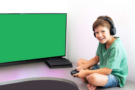 Teenager boy online plays a computer game with headphones and a joystick, game console.の写真素材