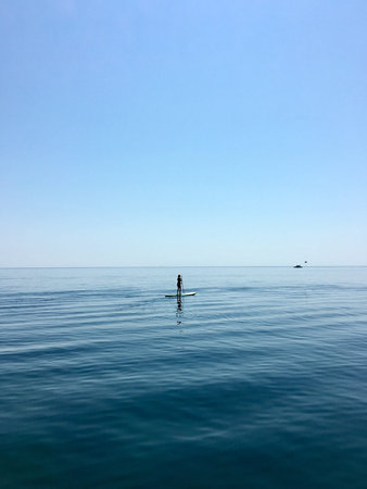 Sup board. water sport. a young man stands on a board in the sea