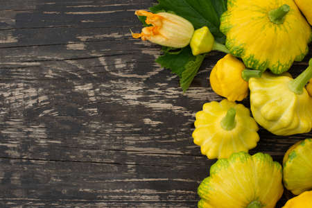 Patisson, Squash, dish-shaped pumpkin, raw vegetable on a dark wooden backgroundの写真素材