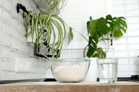 Pouring Water into Flour. Making dough by female hands in white moden kitchen in Scandinavian stile. eggs, flour and waterの写真素材