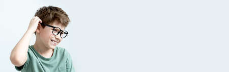 Banner. Surprised boy in a green T-shirt and glasses pensive scratches his head. Copy space. allergyの写真素材