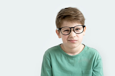Surprised boy in a green T-shirt and glasses pensive scratches his head. Copy spaceの写真素材
