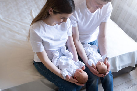 Newborn Identical twins on the bed, on a parents hands. Life style, emotions of kids. Infant Babies...