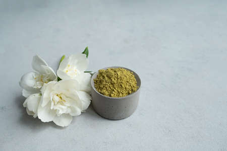 henna powder for dyeing hair and eyebrows and drawing mehendi on hands on a gray cement pedestal with dried flowers or a white flower.の写真素材