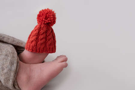 newborn baby feet with Christmas decorations. Funny cute small red Santa hat on baby leg. new year 2022 treeの写真素材