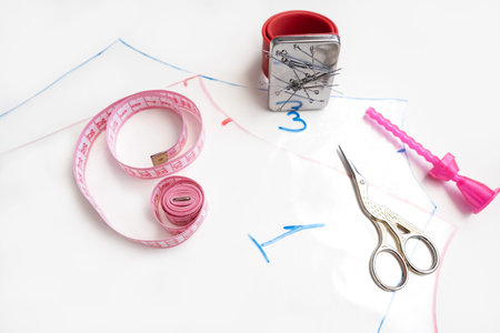 taking measurements on the fabric. Seamstress sewing on the sewing machine in small studio. Fashion...