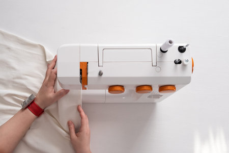 Real middle aged woman tailor sewing clothes using a sewing machine at home.