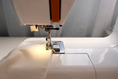 Real middle aged woman tailor sewing clothes using a sewing machine at home. Seamstress working. Hand making clothes in home interior. Female sits enjoying the process of sewing clothes. creative skills design, hobbies, lifestyle and small business conceptの写真素材