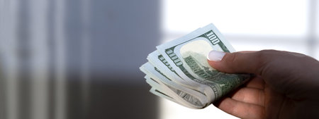 Male hand holding dollar banknotes on blurred background, close-up