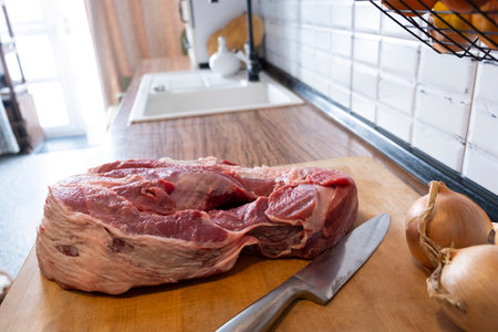 Real men cutting fresh raw meat on board in white kitchen. Preparing pork meat, cooking.の写真素材