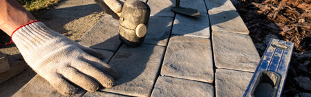Laying paving stones on cement mortar. Laying a garden path made of tiles. Self-laying of concrete paving slabs in the courtyard of the house. do it yourself. DIY. Spatula, level, malletの写真素材