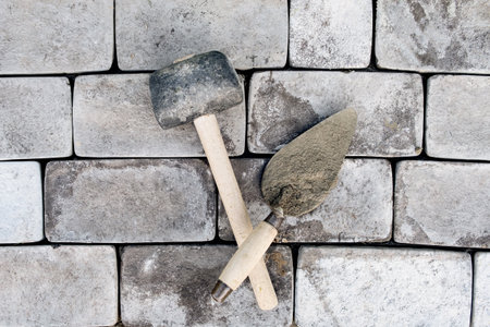 Laying paving stones on cement mortar. Laying a garden path made of tiles. Self-laying of concrete paving slabs in the courtyard of the house. do it yourself. DIY. Spatula, level, malletの写真素材