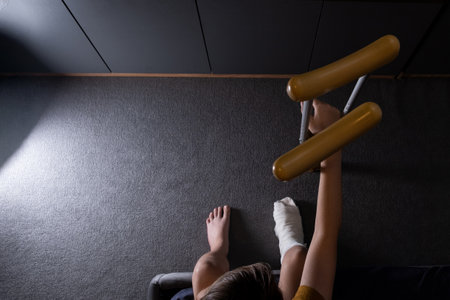 Teenager boy with injured broken leg in a plaster cast on the bed at home with crutches.の写真素材