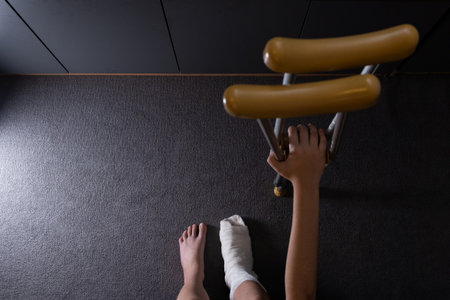 Teenager boy with injured broken leg in a plaster cast on the bed at home with crutches.の写真素材