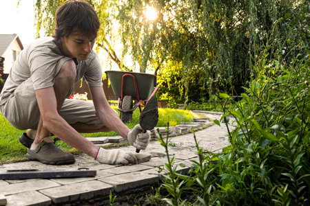 Laying paving stones on cement mortar. Laying a garden path made of tiles. Self-laying of concrete paving slabs in the courtyard of the house. do it yourself. DIY. Spatula, level, malletの写真素材