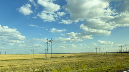 Many high-voltage transmission tower and electricity pylon power lines against blue sky with cloud.