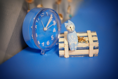 Waiting, a cat on the chest, next to the clock, blue background, nautical theme, blue cat, looking up. Template for polygraphy design, or childish illustrationの写真素材