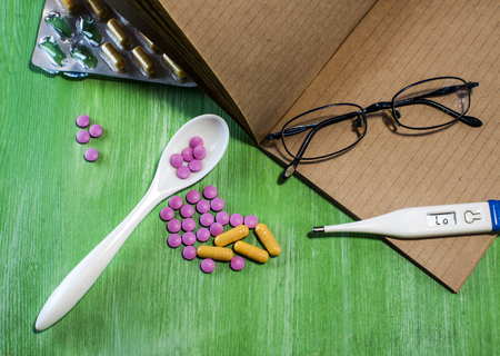 A lot of colorful medication and pills from above on wooden background. Pills, vitamins, capsules, thermometer, glasses.の写真素材