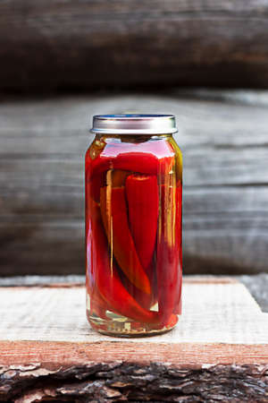 Chili peppers in a glass jar on a wooden table, homemade picklesの写真素材