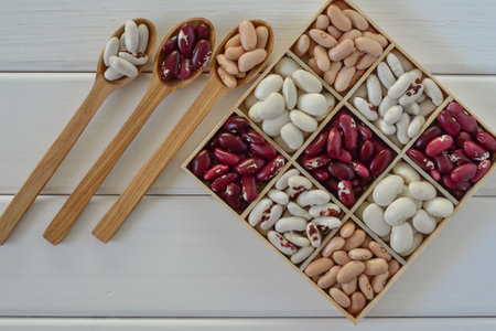 Assortment of beans in wooden box on white wooden background