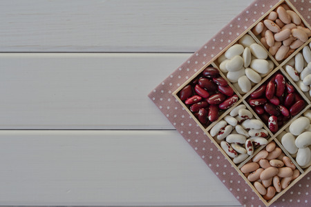Assortment of beans in wooden box on white wooden backgroundの写真素材