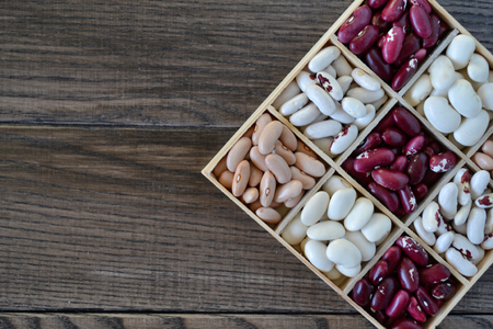 Assortment of beans in wooden box on dark background. Kitchen concept.Chess boardの写真素材