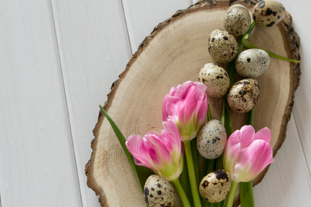 Beautiful tulips with quail eggs on light wooden background. Spring and Easter holiday concept. Top viewの写真素材