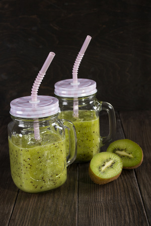 Fresh and healthy green Juice smoothie with kiwi and banana in glass jar. On dark backgroundの写真素材