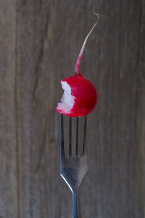 A fork holding up a radishes bitten in halfの写真素材